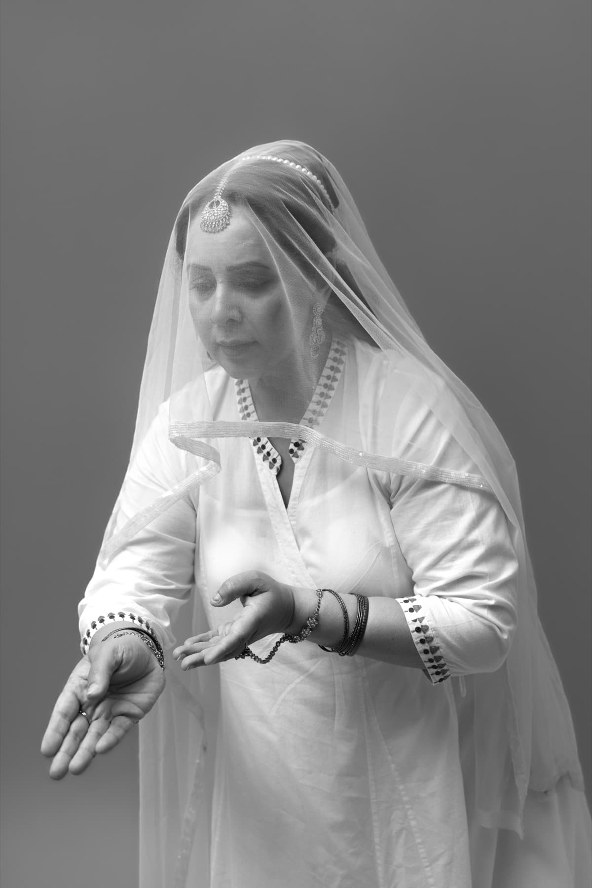 Dr. Dimple Kaur Malhotra in a white veil, in a classical Natya gesture